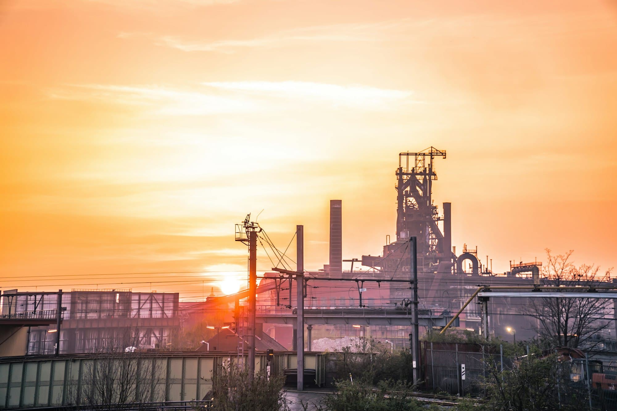 Industrial complex silhouetted against a sunset